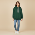 Woman wearing a green hoodie and blue jeans on a beige background