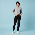 Woman wearing a gray sweater, black jeans, and white sneakers on a light blue background